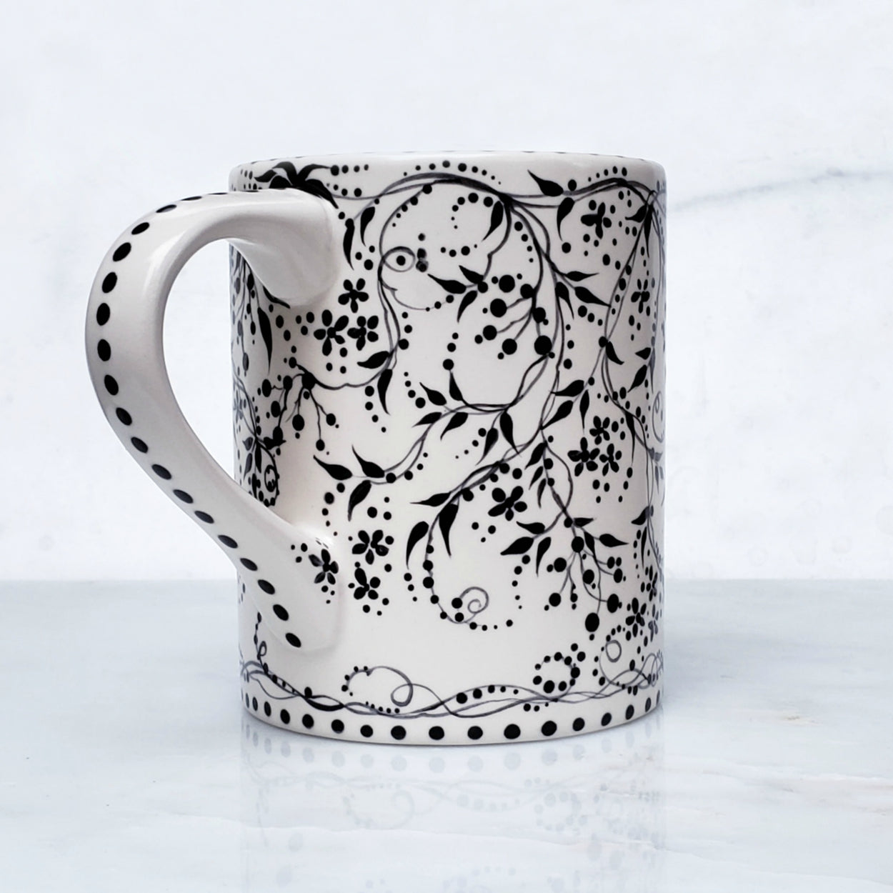 Hand painted black and white mug with trailing vines and berries and tiny flowers. Lovely satin glaze. 16 oz kiln fired ceramic mug