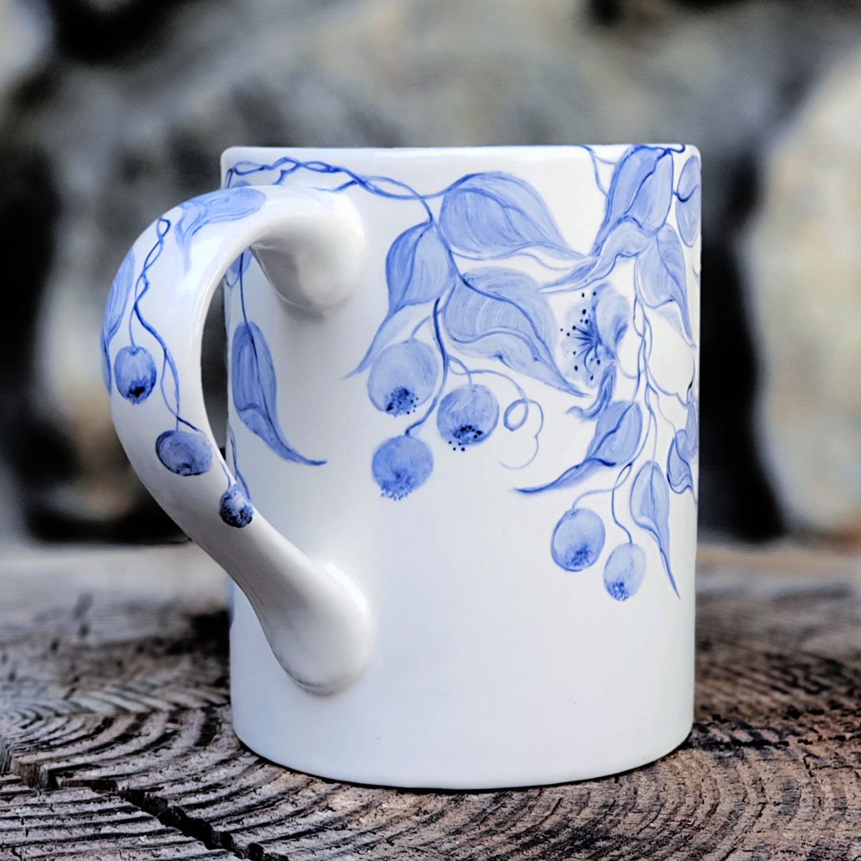 Beautiful blue and white mug.. hand painted with soft trailing blue leaves and blueberries falling over the handle and the entire mug. Kiln fired ceramic hand painted 16 oz. mug