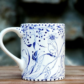 Hand painted blue and white mug with birds and flowers dancing about the entire piece. Whimsical and sweet. 16 oz kiln fired ceramic mug