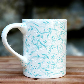 The sweetest aqua and white hand painted mug with the softest satin glaze! Tiny aqua vines and flowers cover the entire piece swirling all about. White polka dots tucked in make it feel so good in your hands. 16 oz kiln fired ceramic mug