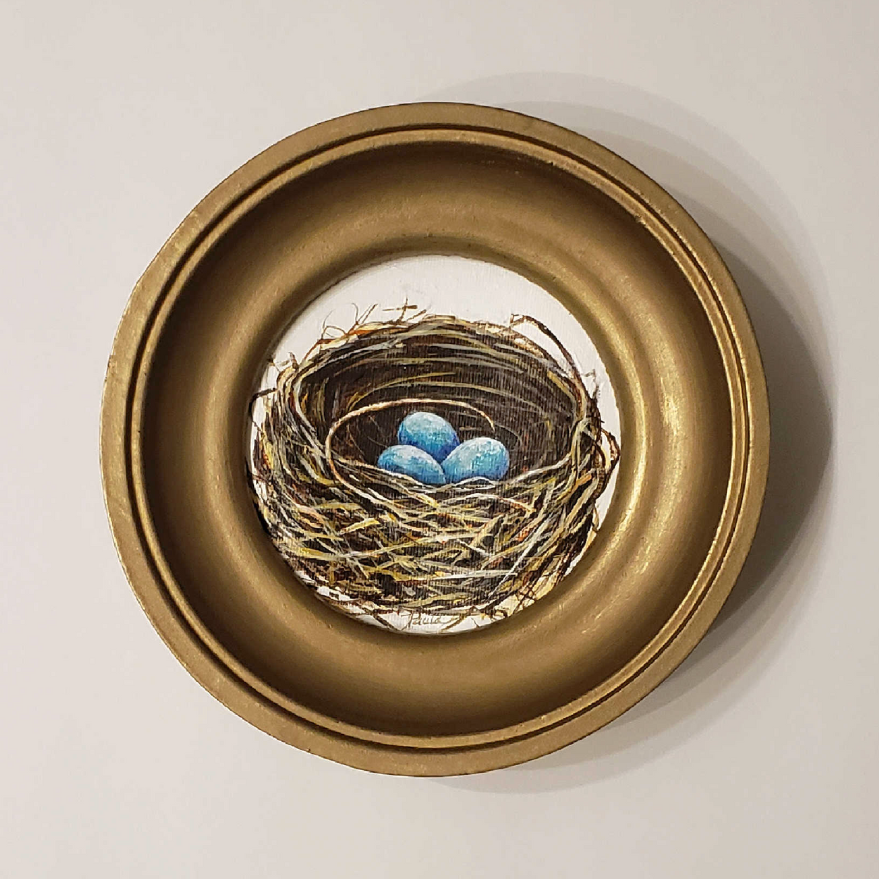 The sweetest little birds nest painted with browns and golds and three aqua eggs. Framed in a vintage style gold frame ... 6 inches round.